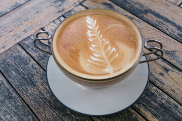 Latte art. Cup of cappuccino on an artistic wooden table. 