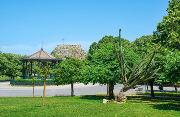 The Spianada Music Pavilion in Platia Leonida Vlachou Park in the historic centre of Corfu Old Town, Greece. The 15th century Old Fortress in the background. UNESCO 