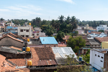 Rooftops in Shravanabelagola provide a glimpse into daily life, with a mixture of colorful houses and modern buildings under a clear blue sky.