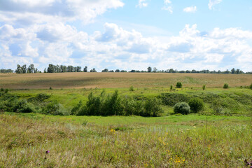 Fototapeta premium a valley with a field and sky with clouds and sunshine