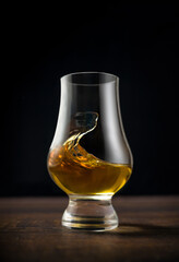 Close-up of single malt whiskey or scotch whisky tasting glass on dark wooden table