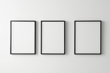 three empty picture frames hanging on a wall in a white room