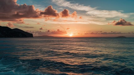 Obraz premium Tranquil sunset over calm sea waters with vibrant orange and purple hues, clouds reflecting sunlight, creating a serene coastal landscape.