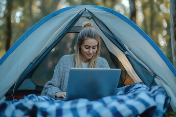 Horizontal shot of a young woman camping outdoors relaxing in a tent using her laptop copyspace student trip studying working online connection relaxation peaceful