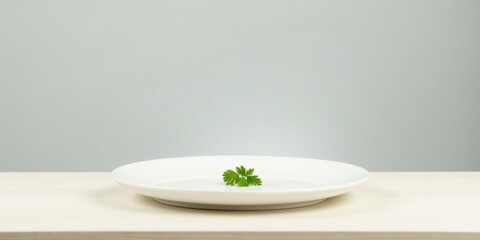 A solitary sprig of fresh herb rests delicately on a pristine white plate, positioned centrally on a light wooden surface against a muted background.