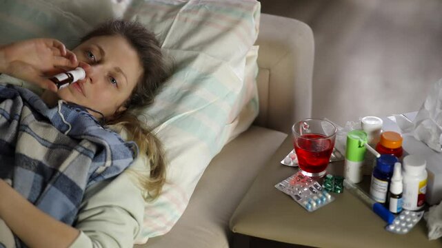 Sick Patient Lying In Bed Using Nasal Spray For Rhinitis Relief. Treatment Of Seasonal Allergy And Virus Infection