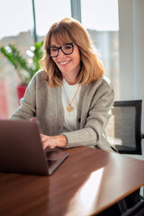 Senior businesswoman with laptop sitting at office desk and working