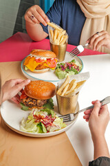 Lifestyle food photography of gourmet burgers in a cafe environment, friends enjoying a meal together.