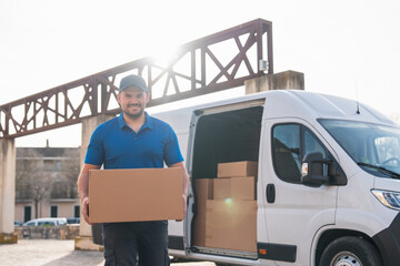 Smiling delivery driver handing over package in front of van. Delivery driver concept in a van. Man...