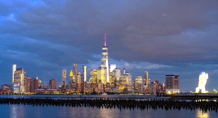 Obraz premium New York city. NYC cityscape. Lower Manhattan and One World Trade Center in New York Cit. Skyscrapers of Manhattan located near rippling water of New York bay against blue sky. New York skyscrapers.