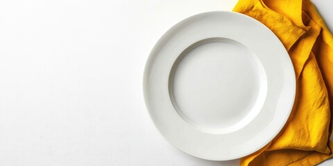 Empty white plate positioned on the left with a vibrant yellow napkin draped artistically on a clean white backdrop creating a minimalist composition