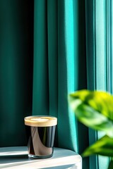 A vibrant glass of dark coffee sits on a side table, contrasted by lush green curtains and a hint of a leafy plant in the foreground.