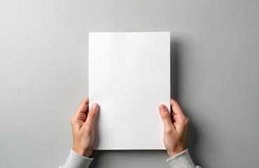 Hands holding white blank paper sheet mockup isolated on gray background. Arm in shirt hold clear brochure template. Leaflet document surface simple print display.