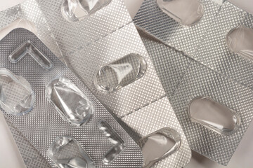 A close-up shot of used blister packs of pills, emphasizing the empty compartments and the metallic...