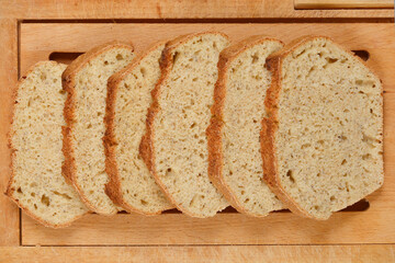 Slices of homemade bread with chia seeds are arranged on a wooden cutting board, showcasing the texture and healthy ingredients