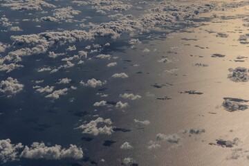 Aerial view of clouds over a shimmering ocean.