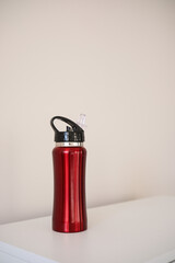 Obraz premium A Stylish Red Water Bottle Placed on a White Surface, Perfect for OntheGo Drinks or Workouts