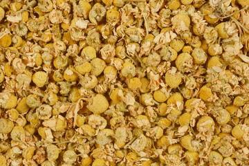 A close-up shot of dried chamomile flowers, showcasing their delicate petals and yellow centers.