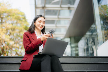 Fototapeta premium Confident Asian woman with a smile standing holding notepad and tablet at out side office.
