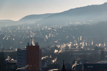 Fototapeta premium viele kleine Schornsteine qualmen im morgendlichen Gegenlicht bei Minusgraden
