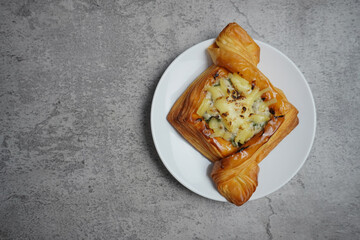 Savory puff pastry with melted cheese and mushrooms on top. Served on a white plate on a gray table.