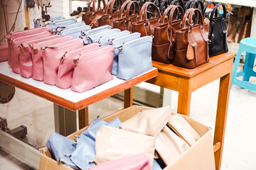 Rows of blank women's leather bags in various colors on a wooden table