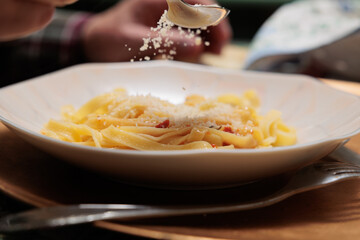 dettagli di un piatto di tagliatelle con sugo di carne mentre vengono condite con del formaggio...