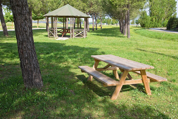 Wooden picnic table with bench in a public park, offering shaded