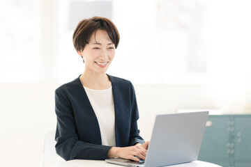 オフィスでパソコン作業をしているジャケットを着た女性。