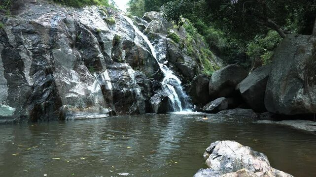 A man swims in a waterfall swimming under a stream of water