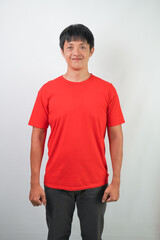 Confident young asian man wearing red shirt is standing over white background.