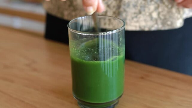 Mixing spirulina powder with natural green juice for detox.