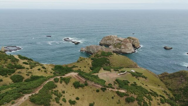Aerial view of the stunning Muelle De Las Almas in Chonchi, Chile, showcasing the dramatic coastline and the vastness of the Pacific Ocean. Dolly Right