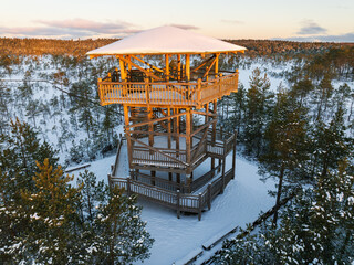 Aerial view of the Viru Bog in winter, with a watchtower silhouetted against the setting sun. Close...