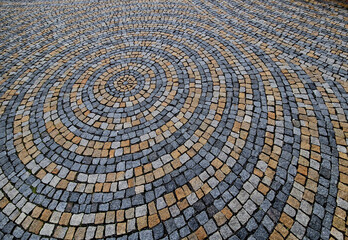 stone paving in the square folded into circles with a larger tile in the middle of the gray granite...