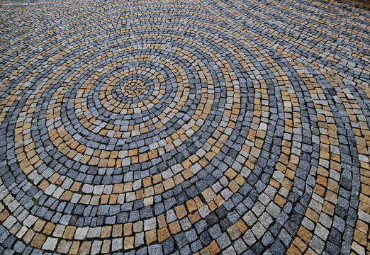 stone paving in the square folded into circles with a larger tile in the middle of the gray granite paving. the circles on the water are symbolic of the paving, the big and the small blend together - Powered by Adobe