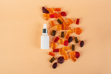 Plastic white tube for cream or lotion. Skin care or sunscreen cosmetic with stylish props and fruit gummi on cream background.