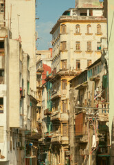 Fototapeta premium Vertical shot of tall, old colonial buildings cramped together in Old Havana, Cuba, shot in an alley street during golden hour. Cramped architecture photography in rich warm tones