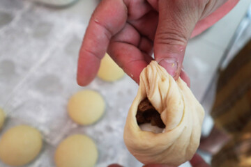 old woman hands kneading dough, making stuffed meat steamed bun in home kitchen