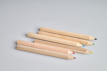 Six raw wooden colored pencils on white background