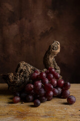 View of bunch of red grapes on vine trunk, dark background, vertical with copy space
