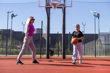 mother and daughter play basketball on a beautiful sunny day.