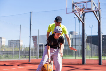 Obraz premium Father and teenage daughter playing basketball outside at court