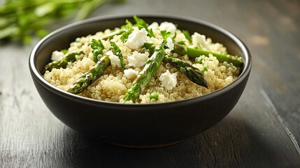 A gourmet-style quinoa bowl with grilled asparagus and feta cheese, set on a minimalist dark wooden surface with soft, natural lighting