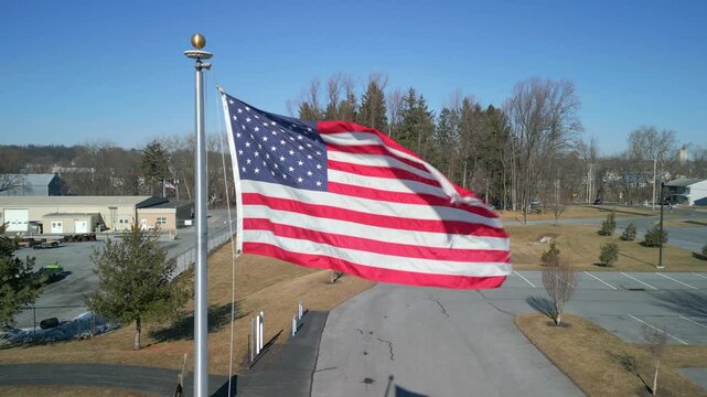 Aerial drone view of an American fag blowing in the wind on a flag pole.