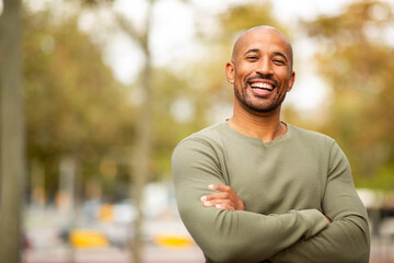 fit and fashionable man standing with arms crossed in urban landscape.