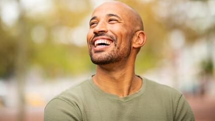 Close up bearded, bald man laughing and looking away outdoors