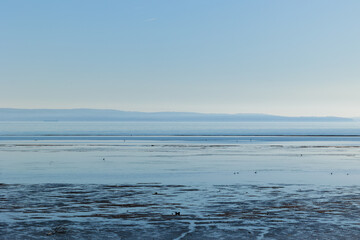 Obraz premium ambiente naturale costiero del Mare Adriatico con bassa marea, vicino al Golfo di Trieste, colorato di arancione dalla luce del sole al tramonto, in inverno