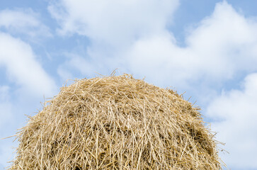 Haystack against a blue sky with clouds