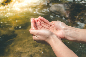 Hands cupping water in a natural setting